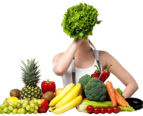 Frau mit Salt vor dem Gesicht und viel Gemüse und Obst vor sich.