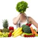 Frau mit Salt vor dem Gesicht und viel Gemüse und Obst vor sich.